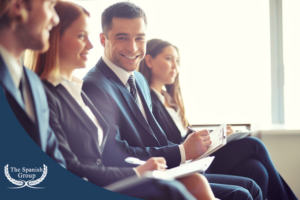 Row of business people making notes at seminar with focus on smiling young man