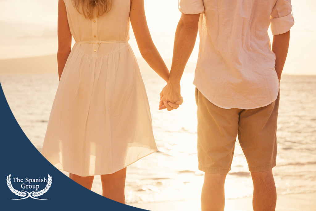 Couple holding hands at sunset on beach. Romantic young couple in love