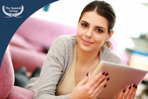 Young beautiful woman lying on the couch and holding tablet computer at home